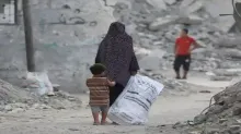 Un niño se aferra al vestido de una mujer mientras pasan por delante de edificios destruidos en Jan Yunis, en el sur de la Franja de Gaza. Los niños y las mujeres conforman el grueso de las víctimas del conflicto en curso entre Israel y Hamás. (Archivo 22.07.2024)